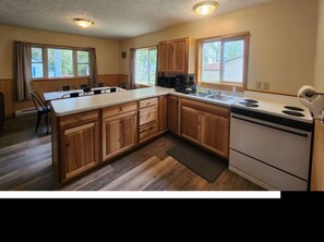 A kitchen with wooden cabinets, a white stove, and a large island with seating.