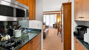 A modern kitchen with a microwave, stove, and sink. A dining area with a sofa and table is visible through an open door. - Luxury Studio Ski-in Ski-Out, Hiking, Mtn Biking, Golf, Fishing (Stowe)