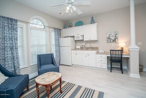 Relax in this cozy living space with a large window offering a view of the outside, a comfortable armchair, and a compact kitchen area.