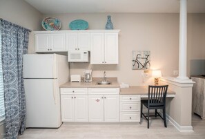 Compact kitchen with a central island, refrigerator, microwave, coffee maker, and sink.