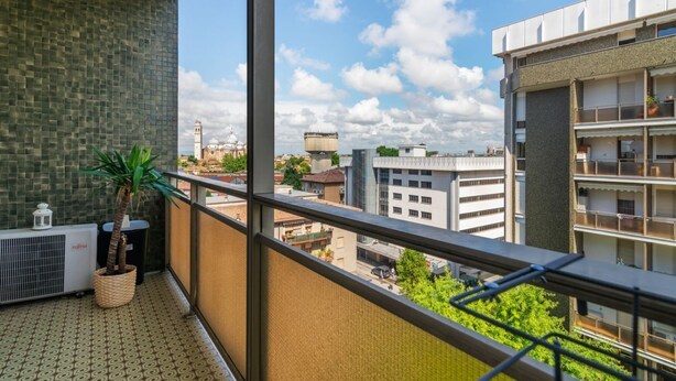 Ein Balkon mit Blick auf eine Stadtlandschaft, darunter ein Turm und moderne Gebäude.