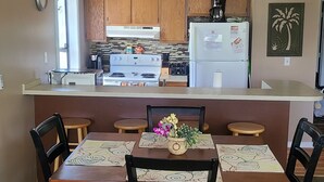 A compact kitchen with wooden cabinets, a central island, and a ceiling fan. - Cozy 2 bed 2 bath in Arcadian Dunes (Myrtle Beach)