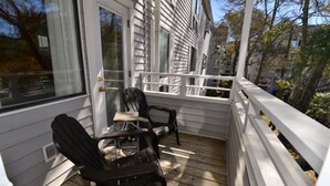 A wooden deck with two black Adirondack chairs, a white railing, and a white door with a window. - Cozy 2 bed 2 bath in Arcadian Dunes (Myrtle Beach)