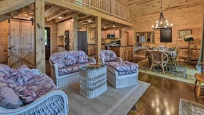 A spacious wooden cabin interior with a dining area, kitchen, and a balcony. - Spacious Pearl Lake Retreat w/ Yard & Private Dock (Kimball)