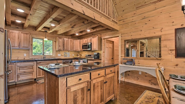 A spacious kitchen with wooden cabinets, a large island, and a dining area with a staircase. - Spacious Pearl Lake Retreat w/ Yard & Private Dock (Kimball)