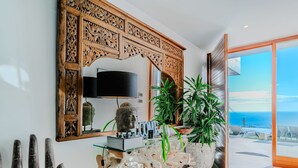 Un interior moderno con un espejo grande de madera tallada, una estatua de Buda y una planta en maceta.