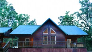 A log cabin with a metal roof, a wooden deck, and a staircase leading to a porch. - The Wild Buck, A Secluded Cabin that Borders the National Forest (Broken Bow)