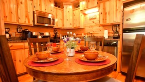 A wooden dining table set with bowls, plates, and cutlery, surrounded by chairs. - The Wild Buck, A Secluded Cabin that Borders the National Forest (Broken Bow)