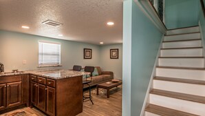 A kitchen with wooden cabinets, a central island, and a dining area with a sofa and coffee table. - Riverview cottage (Grant-Valkaria)