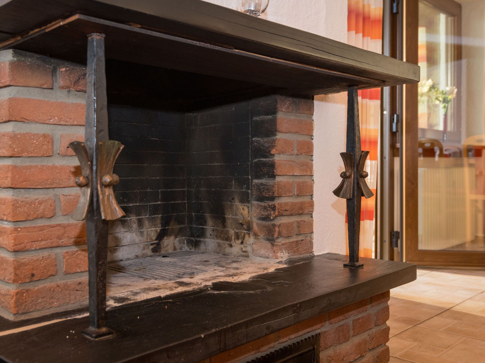 Una chimenea de ladrillo con una repisa metálica y puerta de cristal.