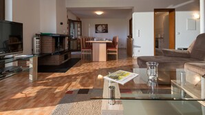 A modern living room with a TV, glass coffee table, and a fireplace. - Eifelnatur (Haus 1) by Interhome (Immerath)