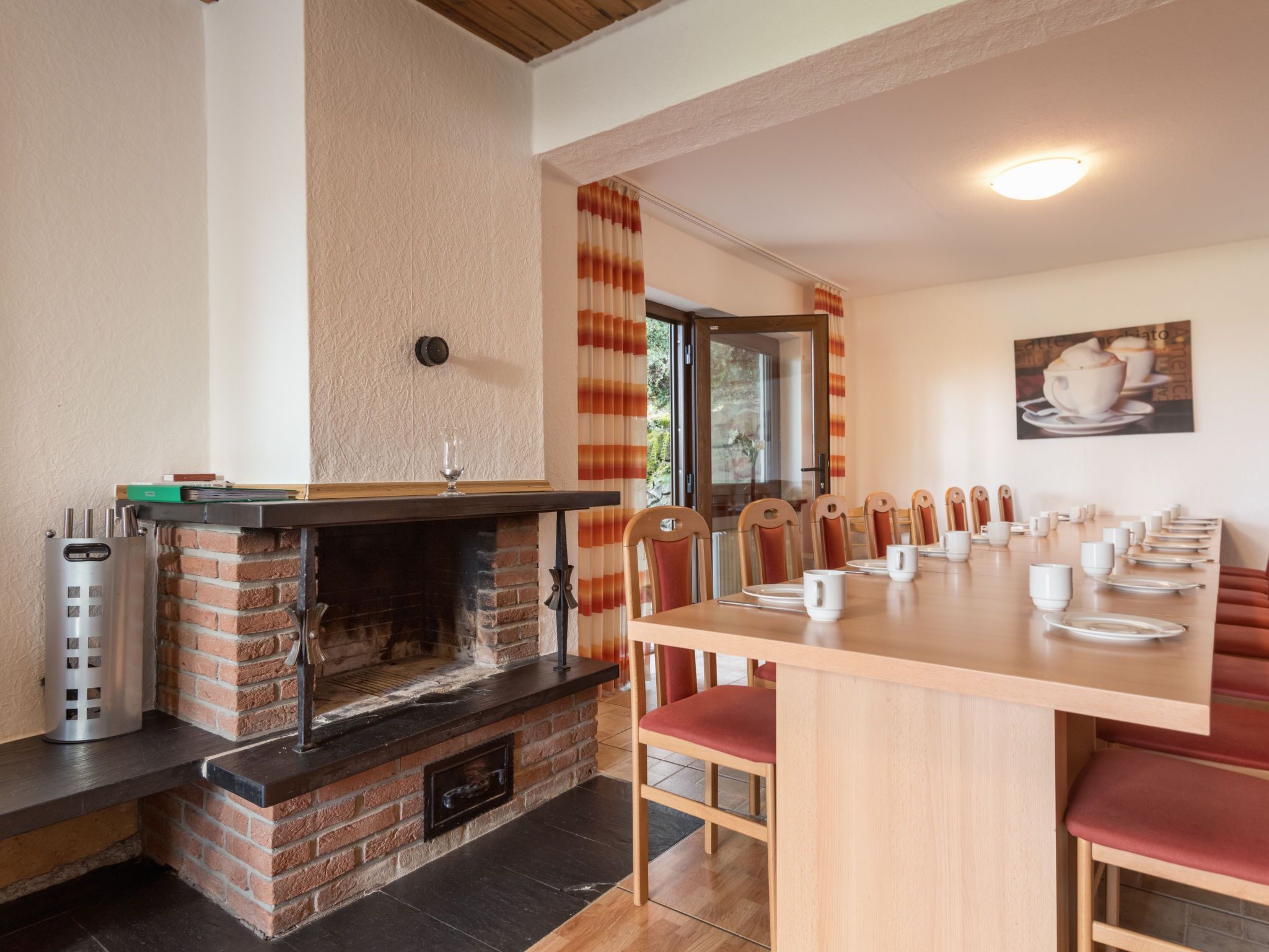 Un comedor acogedor con chimenea de ladrillo, sillas de madera y una mesa larga dispuesta para una comida.