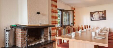 Un comedor acogedor con chimenea de ladrillo, sillas de madera y una mesa larga dispuesta para una comida.