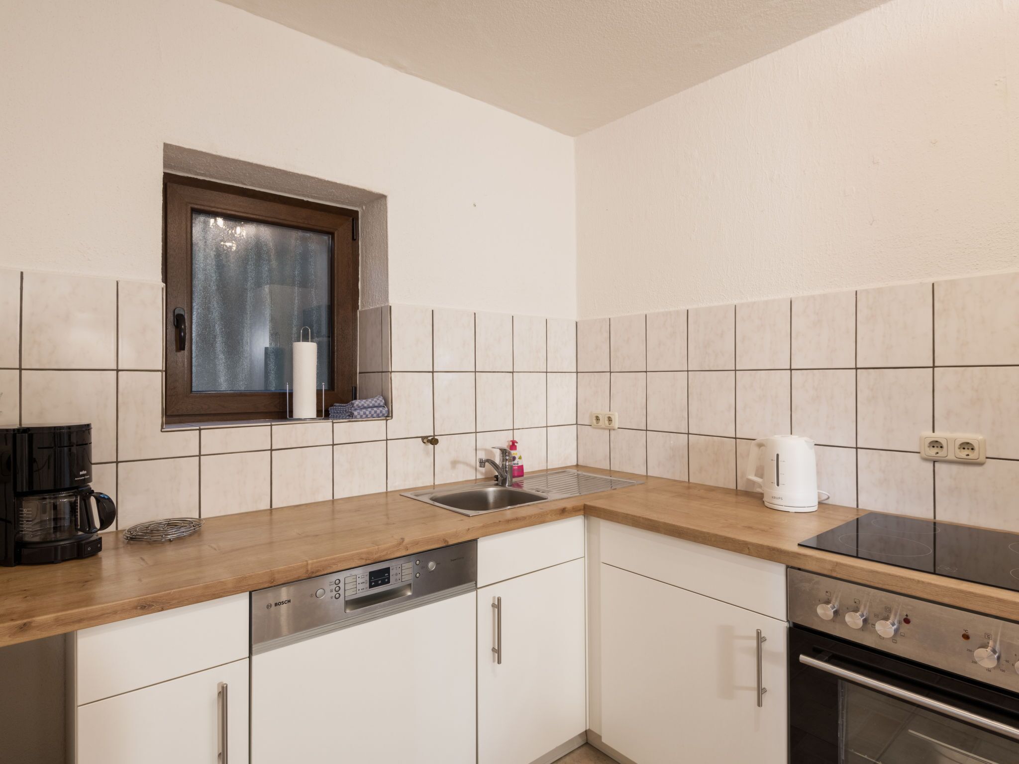 Una cocina equipada con lavavajillas Bosch, cafetera, pileta y estufa.