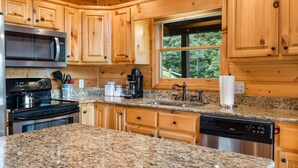 A kitchen with wooden cabinets, granite countertops, a stainless steel microwave, stove, and dishwasher. - Upscale Cabin with Mountain Views - Pet Friendly! (Murphy)