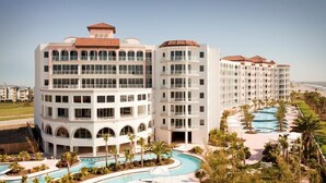 Un hôtel à plusieurs étages doté d’une piscine, de balcons et offrant une vue dégagée sur l’océan.
