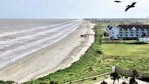 Un hôtel situé sur la côte, avec vue sur la plage, une piscine et un grand bâtiment doté de nombreux balcons.