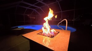Una piscina con una estructura cuadrada para fuego en el centro.
