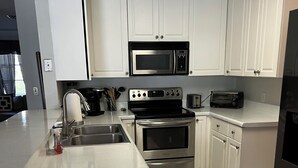 Una cocina moderna con armarios blancos, electrodomésticos de acero inoxidable y suelo de baldosas de mármol.