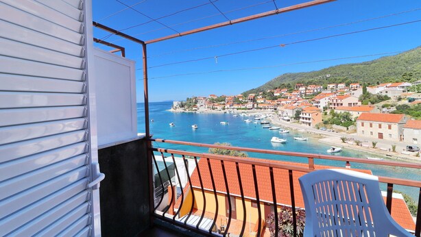 A balcony with a view of a coastal town, boats, and a clear blue sky.