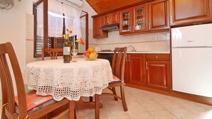 A kitchen with wooden cabinets, a white refrigerator, and a table with a lace tablecloth.
