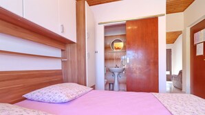 A bedroom with a wooden headboard, a pink bedspread, and a floral pillow.
