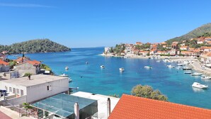 A coastal town with a marina, buildings with red roofs, and a clear blue sea.