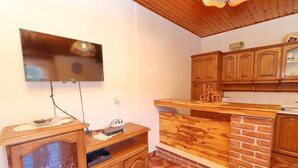 Una cocina con armarios de madera, un televisor montado en la pared y una pared de ladrillo decorativa.