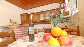 Una mesa de comedor con un bol de vidrio lleno de fruta, una botella de vino y una copa de vino.