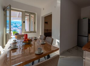 A dining area with a wooden table set for four, a bowl of fruit, and four cups and saucers. - Apartments Peselj-Three Bedroom Apartment with Terrace and Sea View (Smokvica)