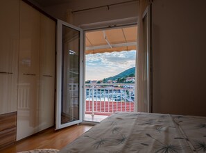 Ein Schlafzimmer mit großem Fenster, einem Bett und einem Kleiderschrank.