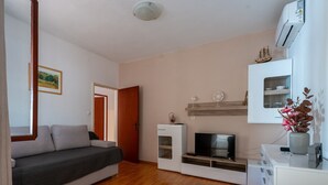 A modern living room with a sofa, TV, and a small table with decorative items. - Apartments Peselj-Three Bedroom Apartment with Terrace and Sea View (Smokvica)