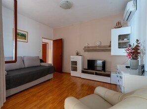 Una sala de estar moderna con sofá, televisor y una mesita con objetos decorativos.
