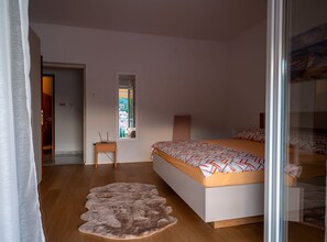 A bedroom with a bed, a small table, a rug, and a window.