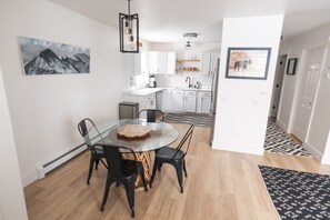 Et moderne køkken med hvide skabe, en backsplash i fiskebensmønster og en central ø.