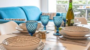 A dining table set with blue glassware, a bottle, and woven bowls. - Les Gemeaux by Interhome (Quiberon)