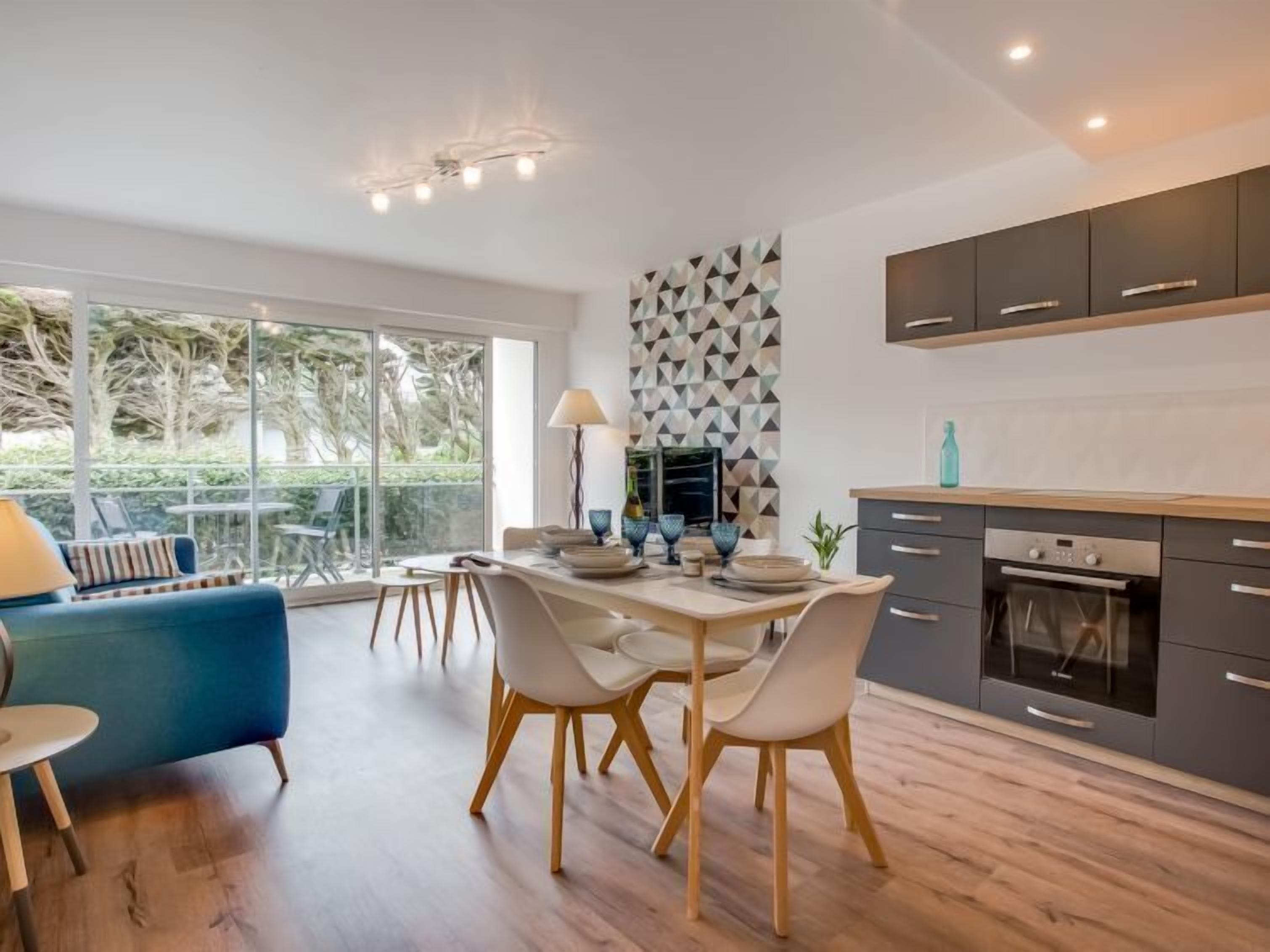 A modern kitchen with a dining area, large windows, and a geometric backsplash.