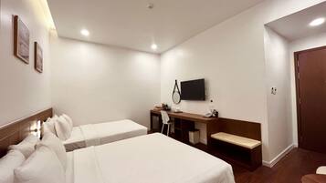 A hotel room with two beds, a desk, a TV, and a door.