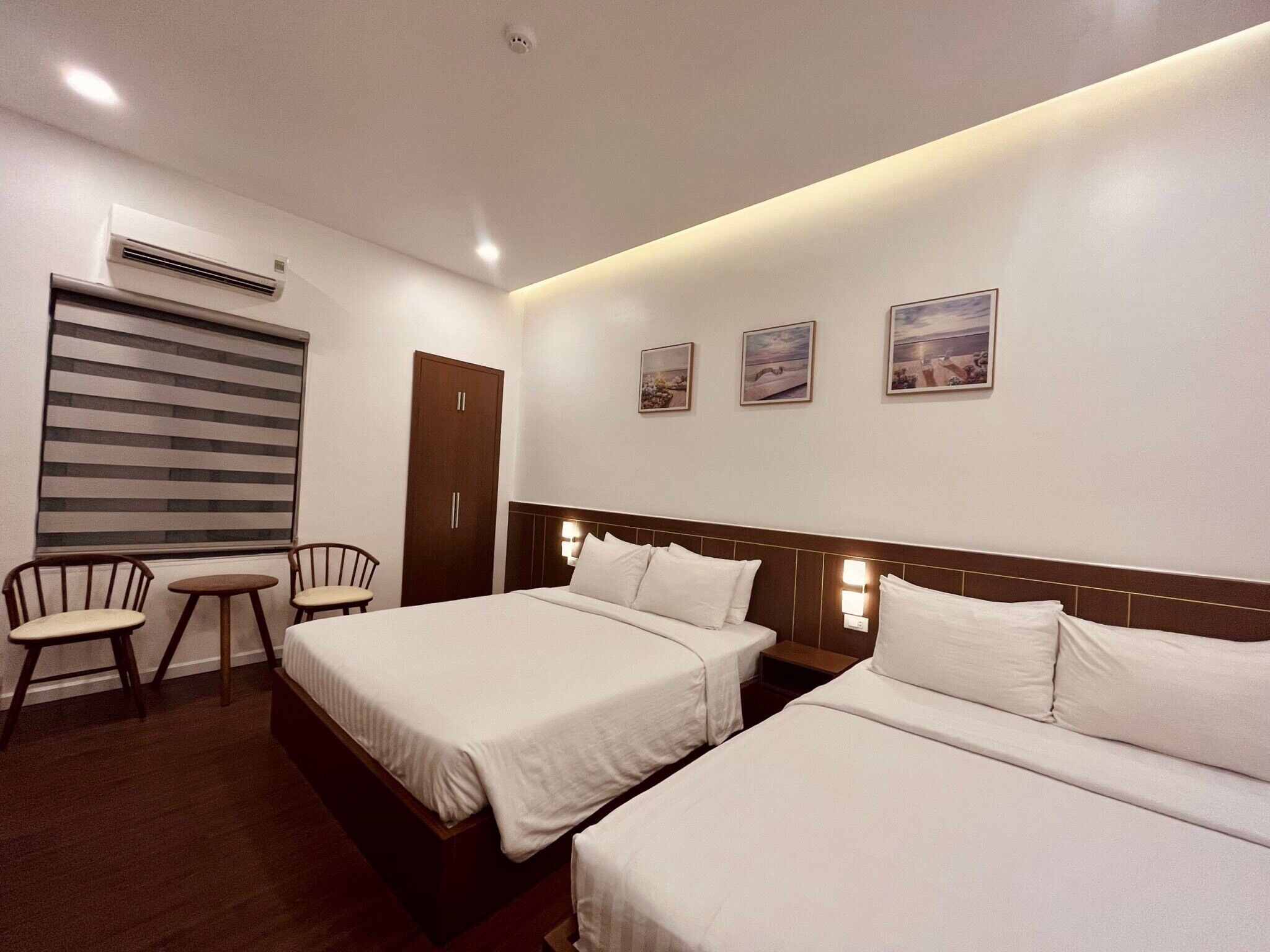 Habitación de hotel con dos camas, un escritorio, una silla y una ventana con persianas.