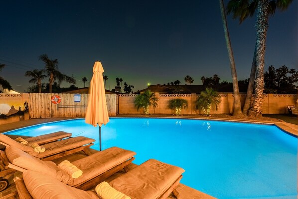 A swimming pool with lounge chairs and palm trees.