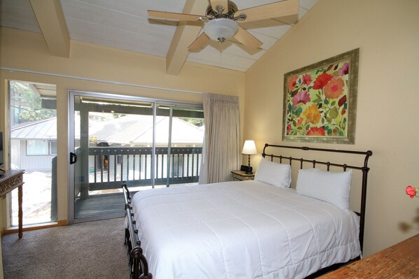 A bedroom with a bed, a ceiling fan, a nightstand, a lamp, and a painting. - Sierra Park Villas #20 (Mammoth Lakes)