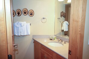 Bathroom features a sink, countertop, and soap dispenser, along with a large mirror and towel rack.