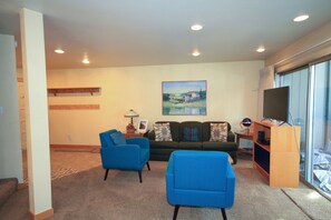 Relax in this stylish living room with a large flat-screen TV, green sofa, and two armchairs.