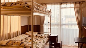 Camera con letto a castello, scrivania, sedia, condizionatore d'aria e finestra con tende.