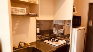 Una cucina compatta con lavello, fornello, microonde e frigorifero.