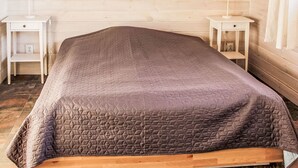 A bed with a quilted cover, two bedside tables with lamps, and a wooden floor. - Dom Przy Cisowym Jarze by Interhome (Jablonowo)