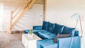 A modern living room with a wooden staircase, a blue sofa, a white coffee table, and a floor lamp. - Dom Przy Cisowym Jarze by Interhome (Jablonowo)