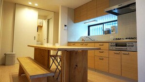 A modern kitchen with wooden cabinets, a built-in oven, and a window above the sink. - Ichijyo PREMIUM (Kyoto)