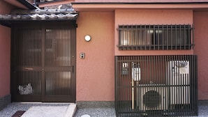 A traditional Japanese gate with a sliding door, a small circular window, and a barred window above. - Ichijyo PREMIUM (Kyoto)