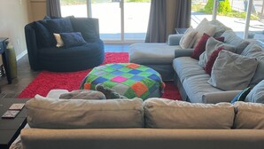 A living room with a large window, a red rug, a blue armchair, and a grey sofa. - Floating Over The Water! (Chelan)